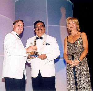 Business leader receiving an international award on stage alongside presenters at a formal ceremony