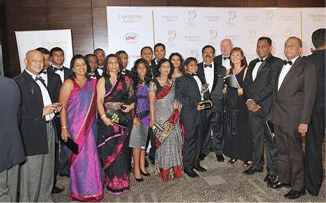 Group of business leaders and guests at an Enterprise Asia awards ceremony posing with a trophy during a formal recognition event