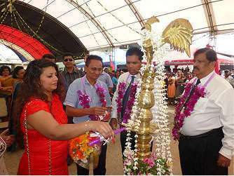 Traditional ceremonial lamp lighting at a cultural or corporate inauguration event attended by dignitaries and guests